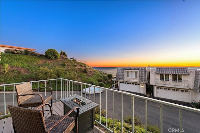 balcony at dusk with a water view and a fire pit