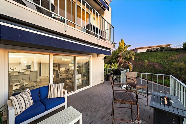 deck at dusk with an outdoor living space with a fire pit