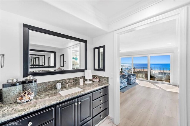 bathroom with vanity, crown molding, wood-type flooring, and a water view