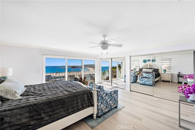 bedroom with crown molding, a water view, access to outside, and light wood-type flooring