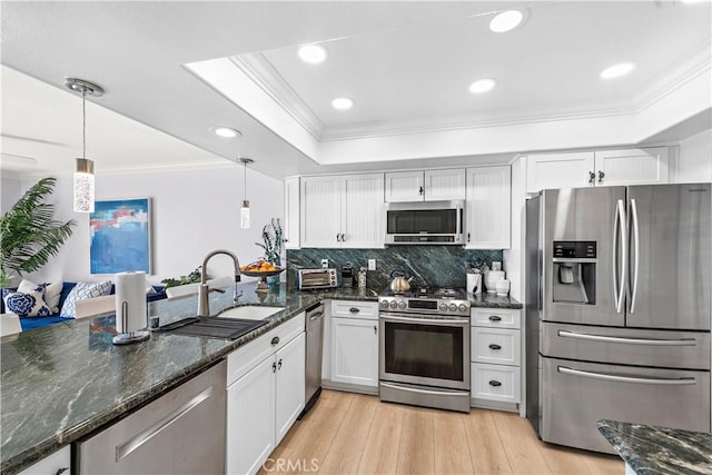 kitchen featuring white cabinetry, stainless steel appliances, decorative light fixtures, and sink