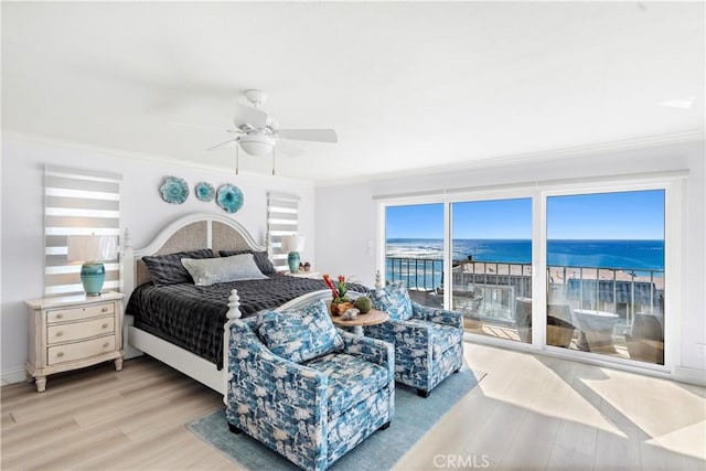 bedroom featuring a water view, ornamental molding, light wood-type flooring, and access to outside