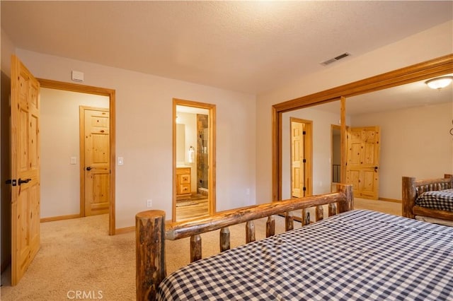 bedroom with light carpet, a closet, and ensuite bathroom