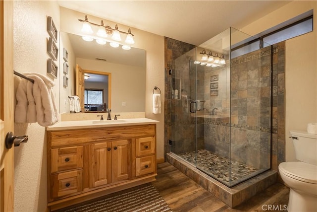 bathroom featuring toilet, vanity, walk in shower, and hardwood / wood-style flooring