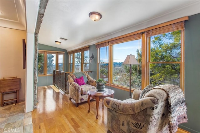 sunroom / solarium featuring vaulted ceiling, a mountain view, visible vents, and a healthy amount of sunlight