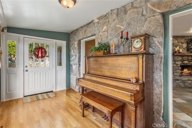 foyer entrance featuring wood finished floors and a stone fireplace