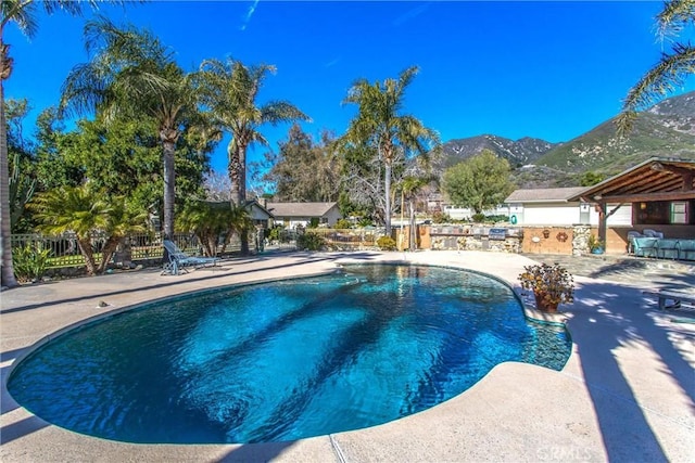 view of swimming pool featuring a patio area, fence, a mountain view, and a fenced in pool