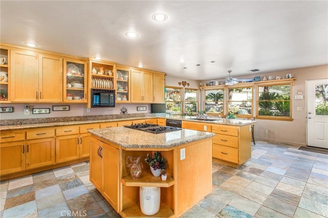 kitchen featuring open shelves, glass insert cabinets, a kitchen island, a sink, and light stone countertops