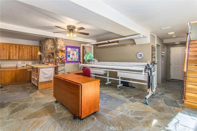 interior space featuring ceiling fan, stone floors, and brown cabinetry