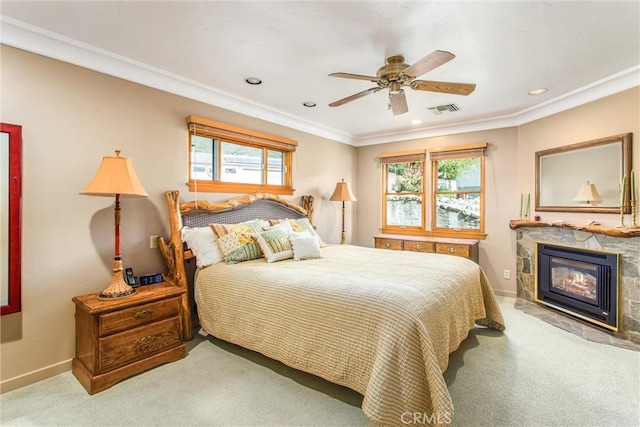 carpeted bedroom featuring a stone fireplace, multiple windows, visible vents, and baseboards