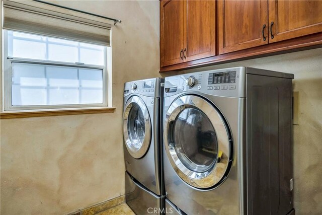 laundry room featuring washing machine and clothes dryer and cabinets