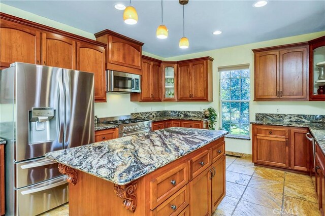 kitchen with dark stone countertops, a center island, hanging light fixtures, and appliances with stainless steel finishes