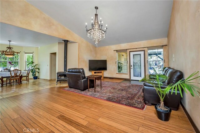 living room featuring a healthy amount of sunlight, light wood-type flooring, high vaulted ceiling, and an inviting chandelier