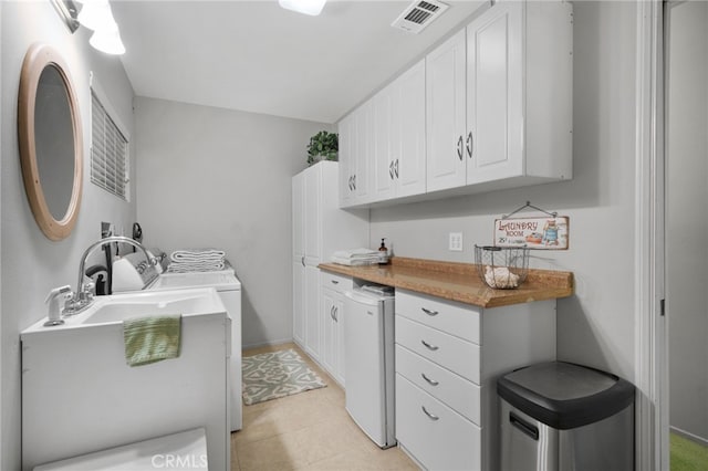 laundry room with light tile patterned flooring, cabinets, and washer / dryer