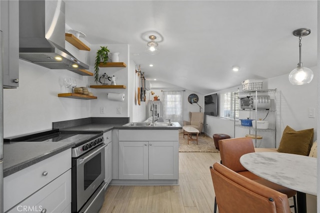 kitchen featuring white cabinets, wall chimney range hood, electric stove, vaulted ceiling, and decorative light fixtures