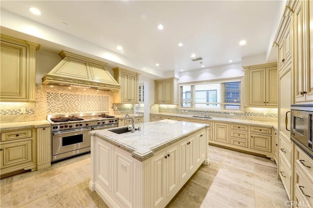 kitchen with sink, stainless steel appliances, an island with sink, decorative backsplash, and custom range hood