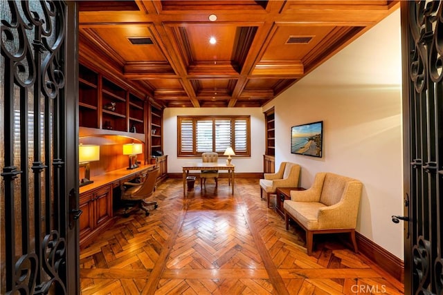 office with built in shelves, built in desk, crown molding, and coffered ceiling