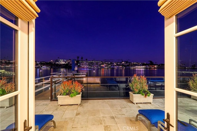 balcony at twilight featuring a water view