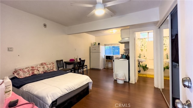 bedroom with ceiling fan, white refrigerator, and dark hardwood / wood-style floors