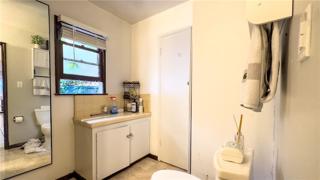 bathroom featuring toilet, tile flooring, and tasteful backsplash