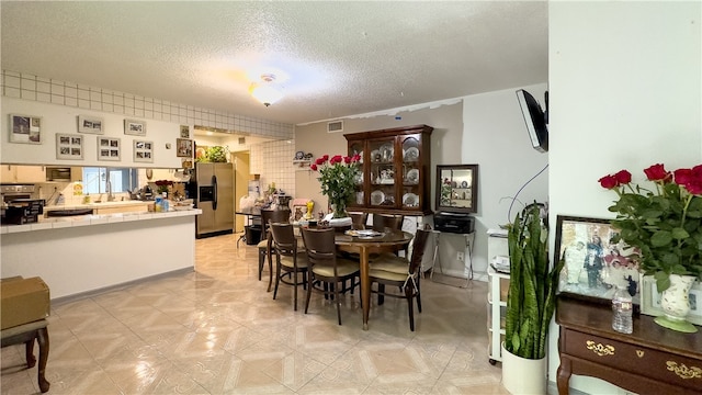 dining space featuring light tile floors and a textured ceiling