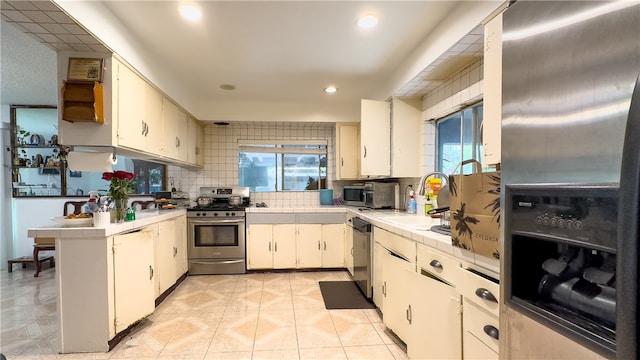 kitchen with sink, appliances with stainless steel finishes, a wealth of natural light, and light tile floors