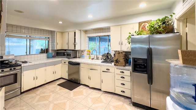 kitchen with tile counters, stainless steel appliances, tasteful backsplash, and light tile floors