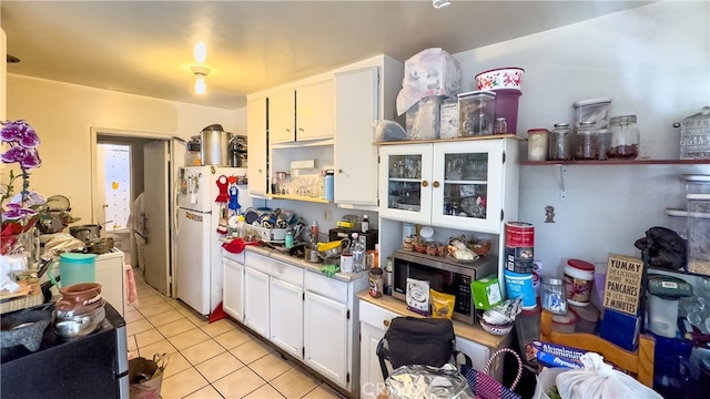 kitchen with white refrigerator, light tile floors, and white cabinets