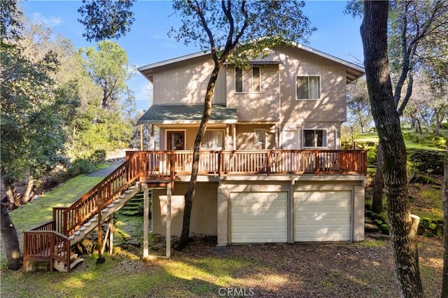 rear view of property featuring a garage and a wooden deck