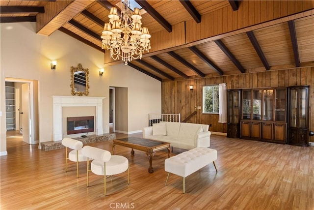 living room featuring an inviting chandelier, light hardwood / wood-style flooring, wooden ceiling, and wood walls