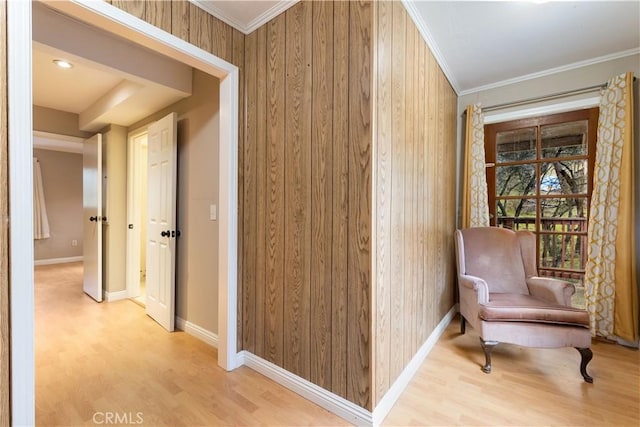 hall with light hardwood / wood-style floors, crown molding, and wooden walls