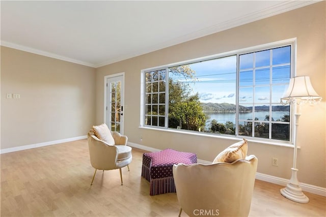 living area with a water view, ornamental molding, and light hardwood / wood-style flooring