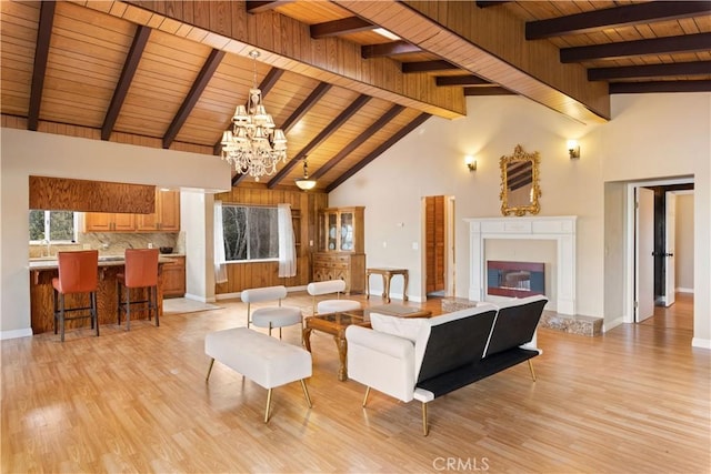 living room featuring wooden ceiling, light hardwood / wood-style flooring, high vaulted ceiling, beamed ceiling, and a chandelier