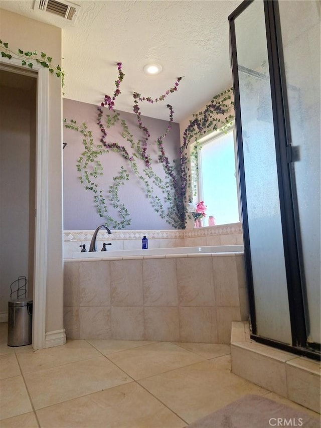 bathroom with tiled bath, tile patterned floors, and a textured ceiling