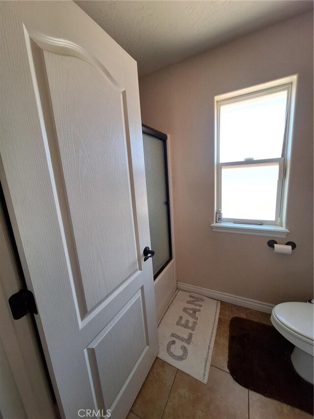 bathroom with toilet, a textured ceiling, and tile patterned floors