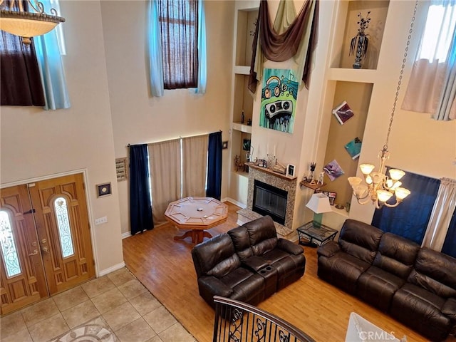 living room featuring built in shelves, tile patterned floors, a notable chandelier, and a healthy amount of sunlight