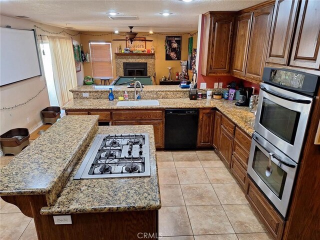 kitchen with sink, appliances with stainless steel finishes, kitchen peninsula, and light tile patterned flooring