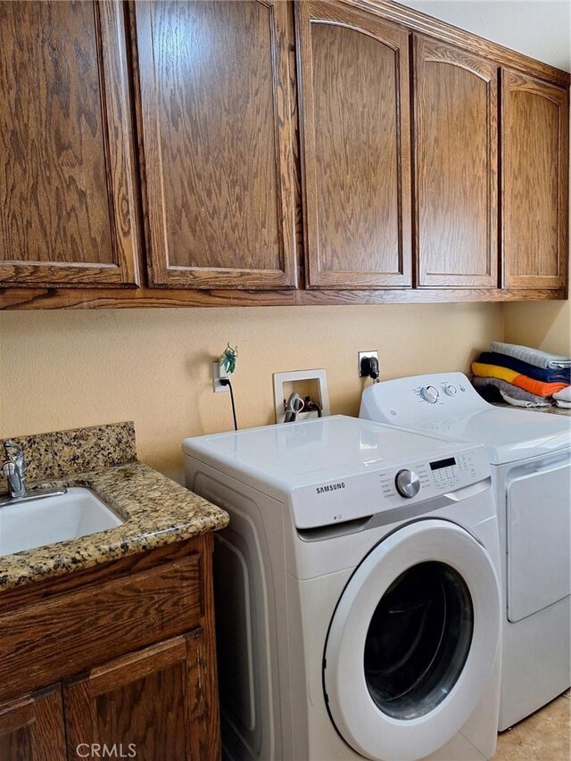 washroom with cabinets, washer and clothes dryer, and sink