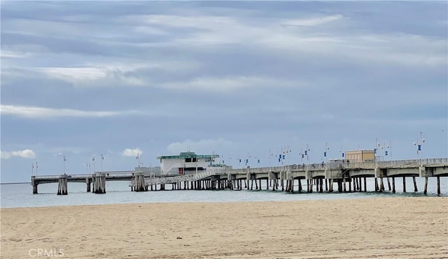 view of dock with a water view and a beach view