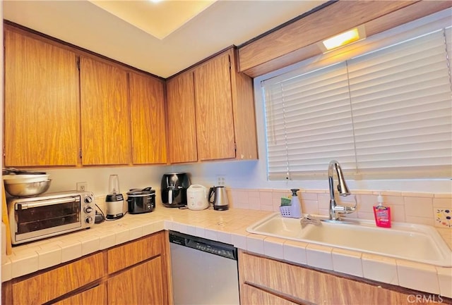 kitchen featuring tile counters, dishwasher, and sink