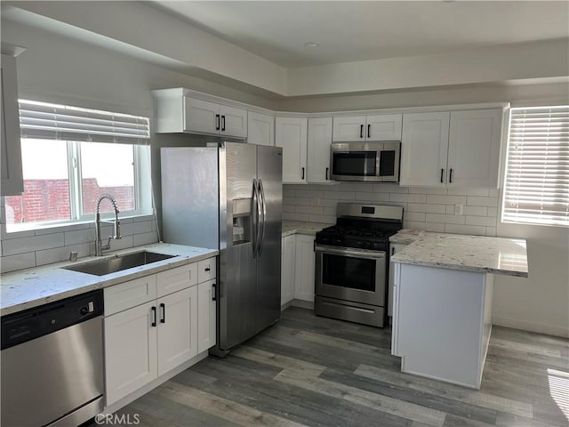 kitchen with white cabinetry, sink, light stone counters, and stainless steel appliances