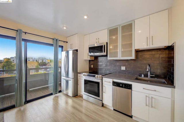 kitchen featuring white cabinetry, backsplash, appliances with stainless steel finishes, sink, and light wood-type flooring