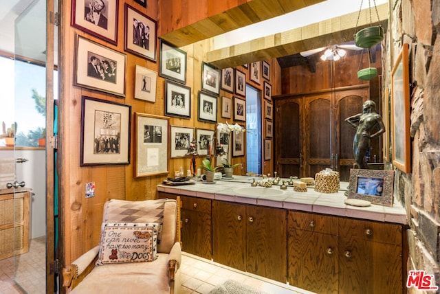 bathroom featuring wooden walls, vanity, and ceiling fan