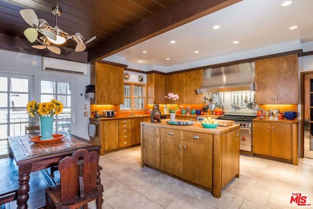 kitchen featuring wall chimney exhaust hood, beamed ceiling, an AC wall unit, decorative backsplash, and a kitchen island