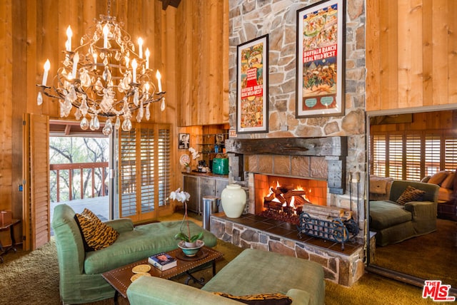 living room with a towering ceiling, a fireplace, wooden walls, and an inviting chandelier