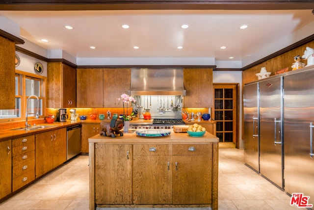 kitchen featuring wood counters, appliances with stainless steel finishes, tasteful backsplash, wall chimney range hood, and a center island