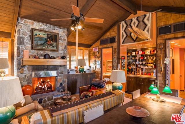 living room featuring wood walls, wooden ceiling, high vaulted ceiling, a stone fireplace, and beamed ceiling