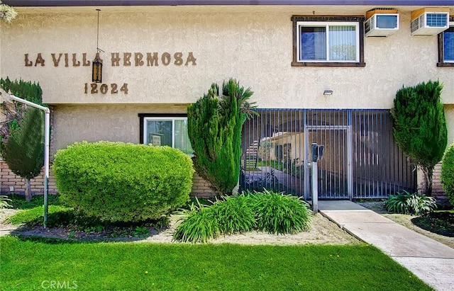 view of front of home featuring a wall unit AC, fence, and stucco siding