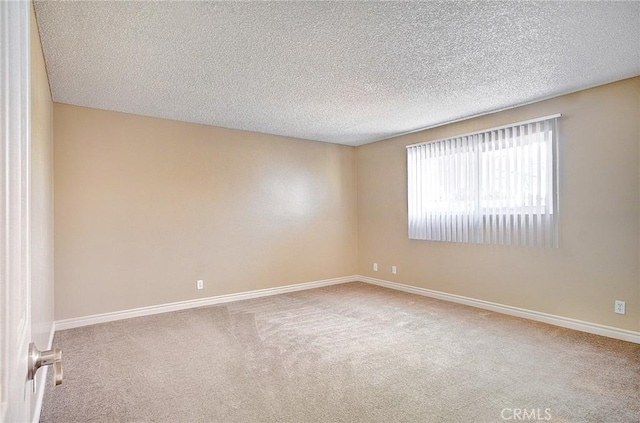 carpeted spare room with a textured ceiling and baseboards