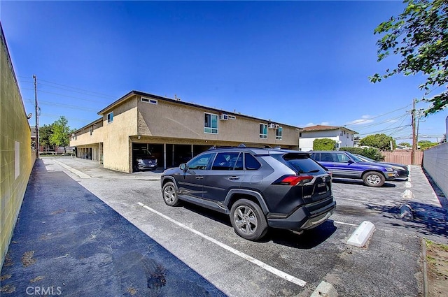 view of front of property with uncovered parking, fence, and stucco siding